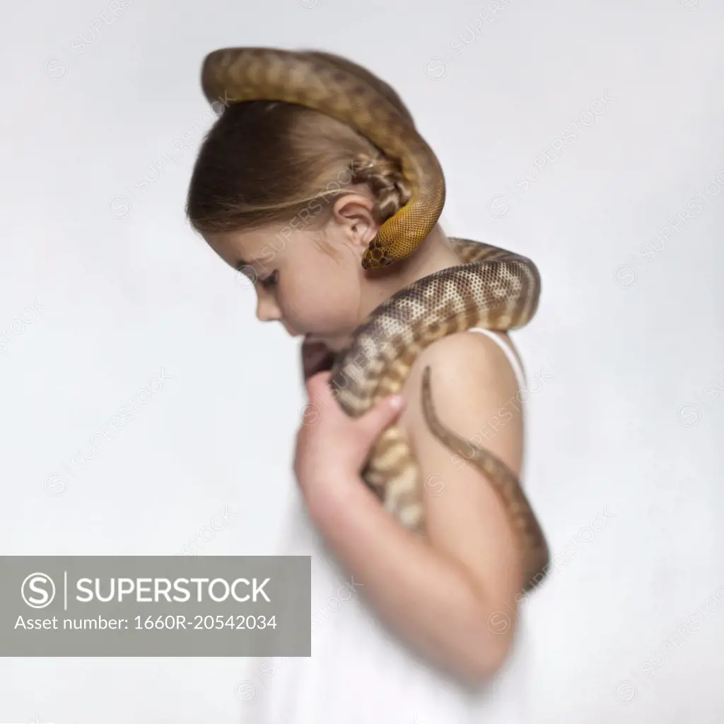 Studio portrait of girl (6-7) with snake