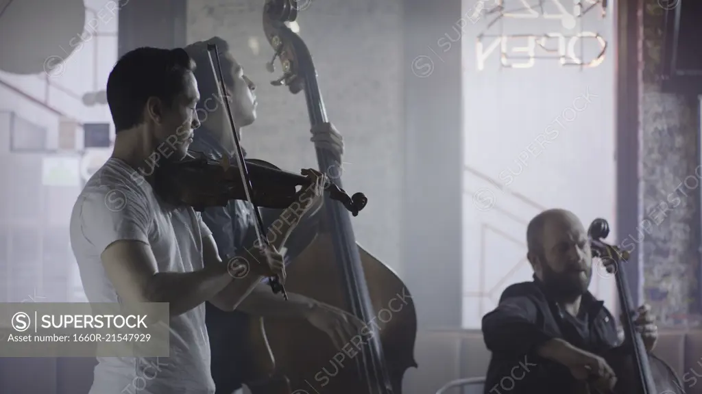 Serious musician playing violin in band in cafe