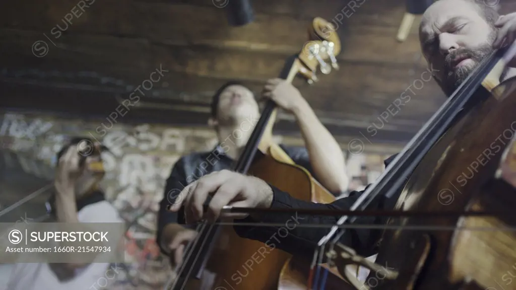 Low angle view of serious musicians playing violin in band in cafe