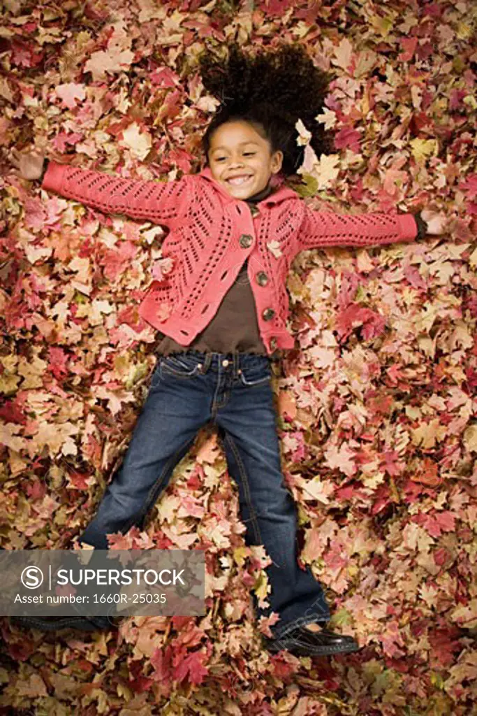 Young girl playing in fallen leaves