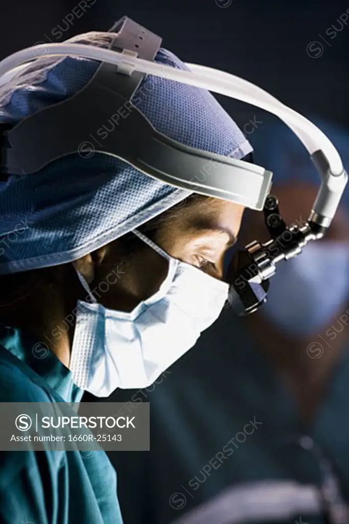 Female doctor in scrubs with head light in surgery