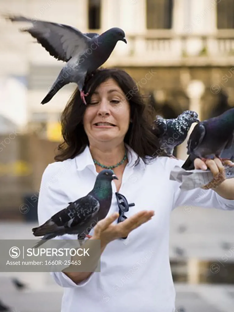 Woman with pigeons and eyes crossed with tongue out - SuperStock