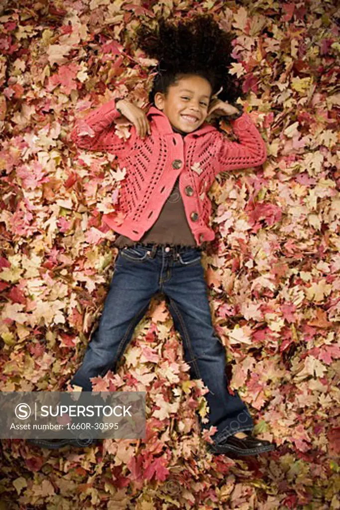 Young girl playing in fallen leaves