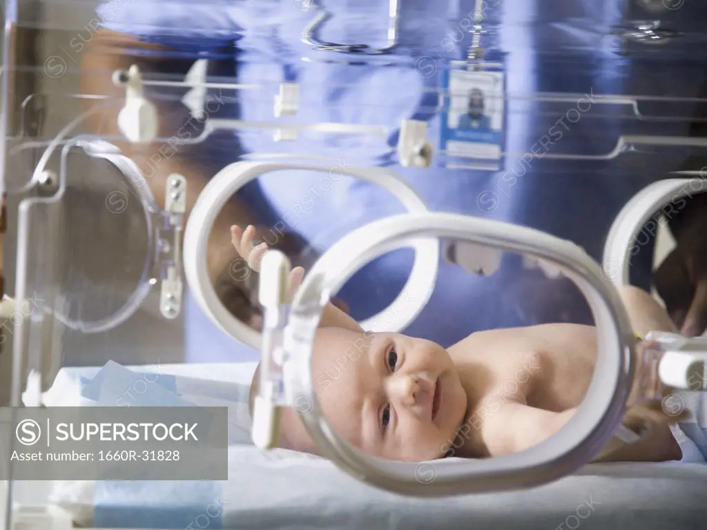 Baby in incubator with man in uniform