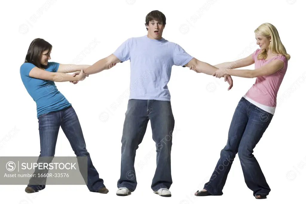 Two girls tugging at arms of boy