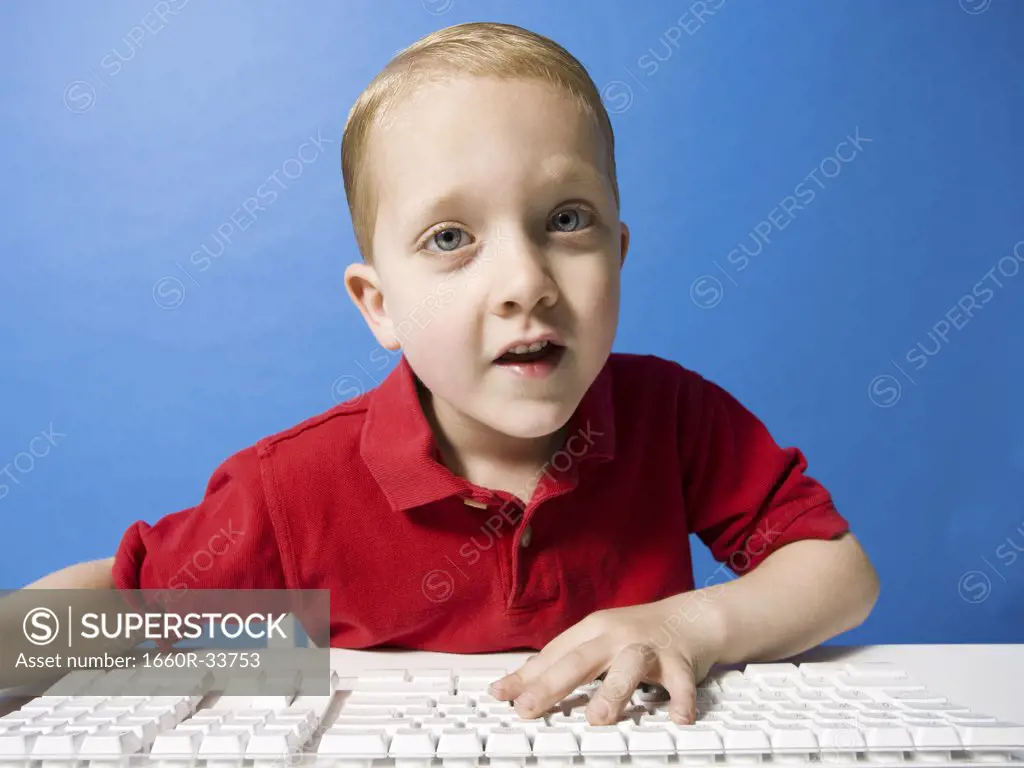 Boy sitting at keyboard smiling