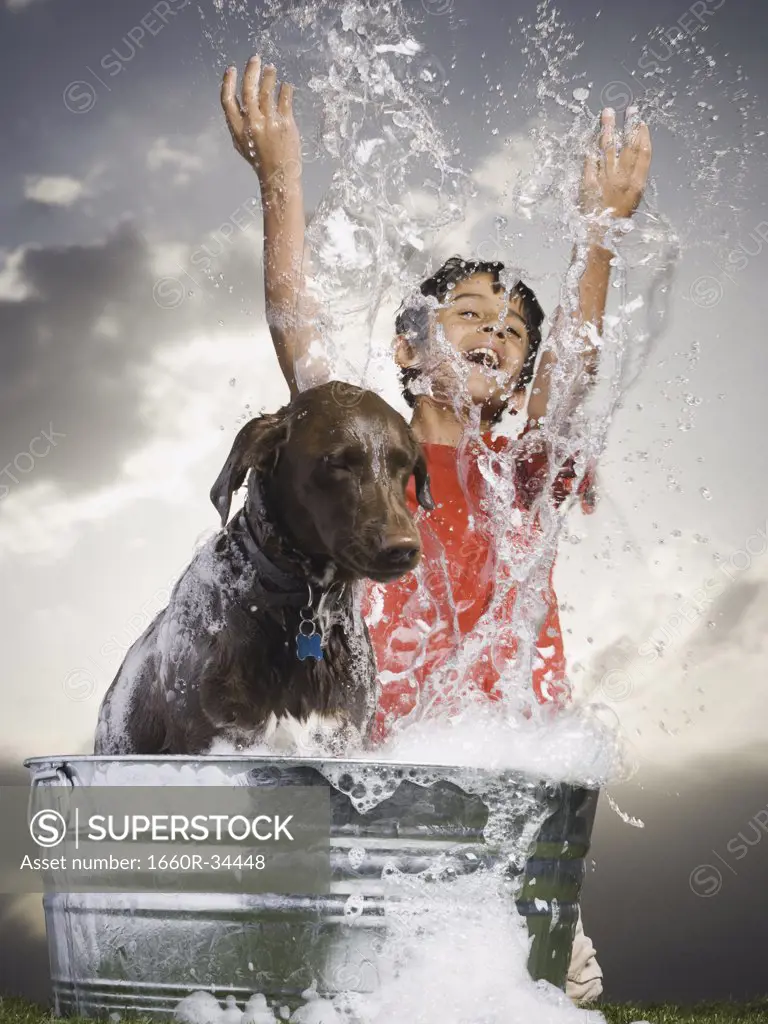 Boy bathing dog outdoors smiling