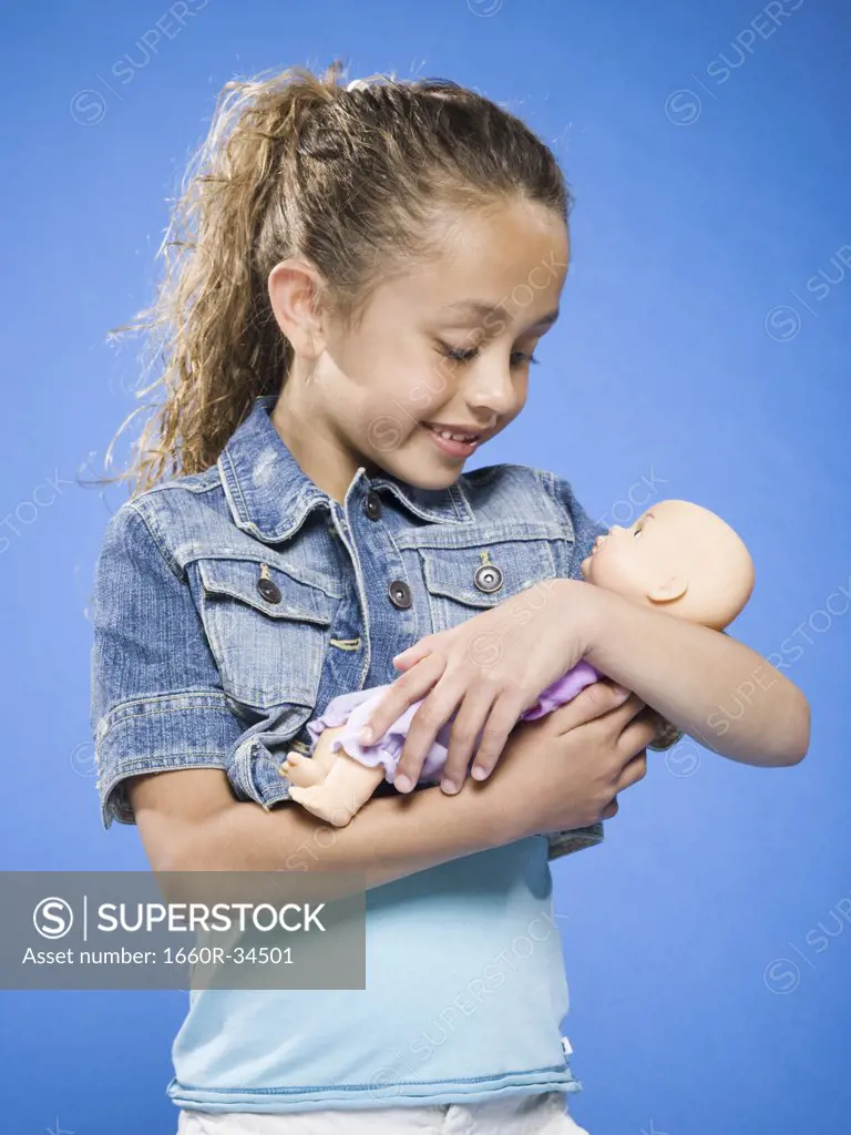 Girl holding baby doll smiling