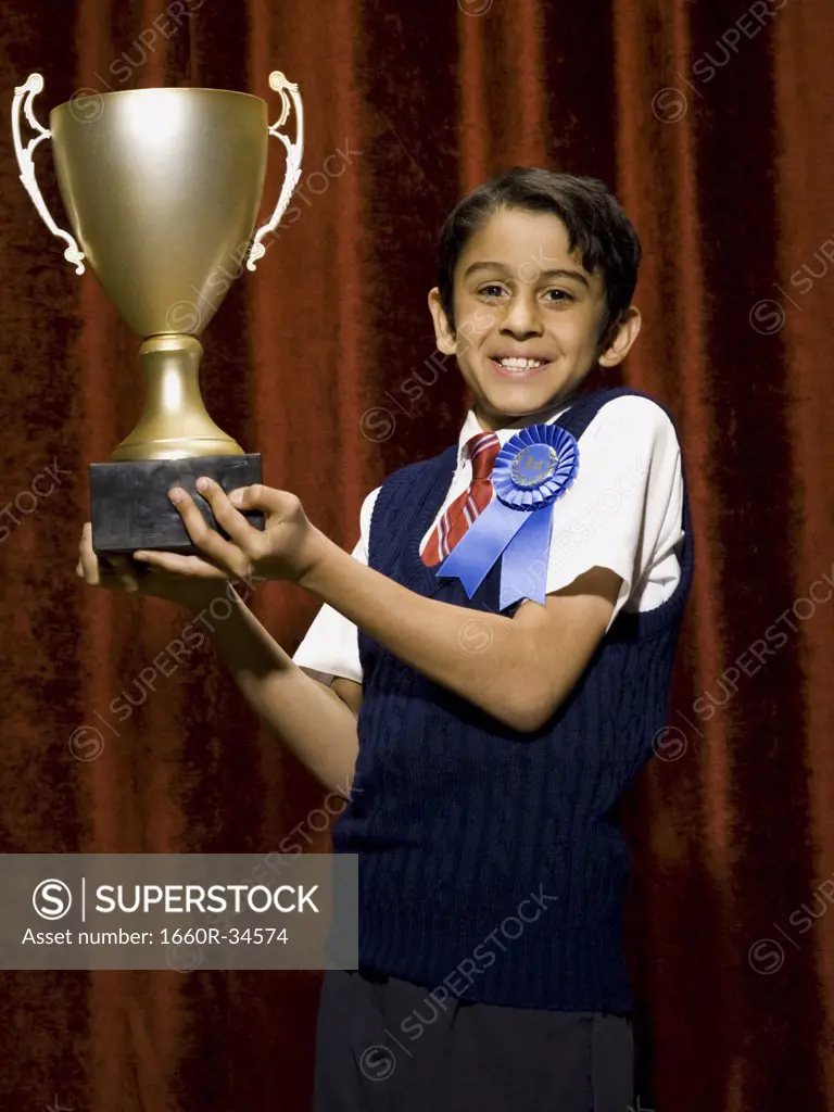 Boy with blue ribbon and trophy cup smiling