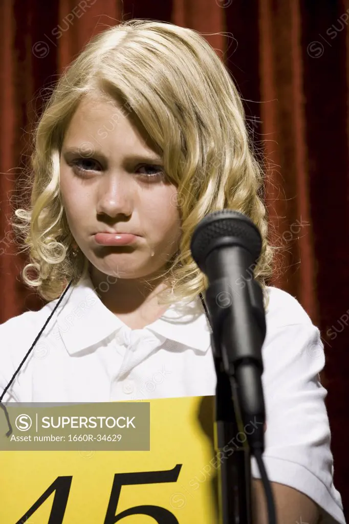 Girl contestant standing at microphone crying