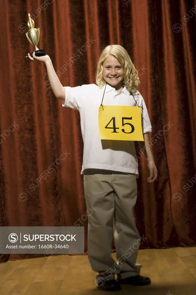 Girl contestant holding trophy and smiling