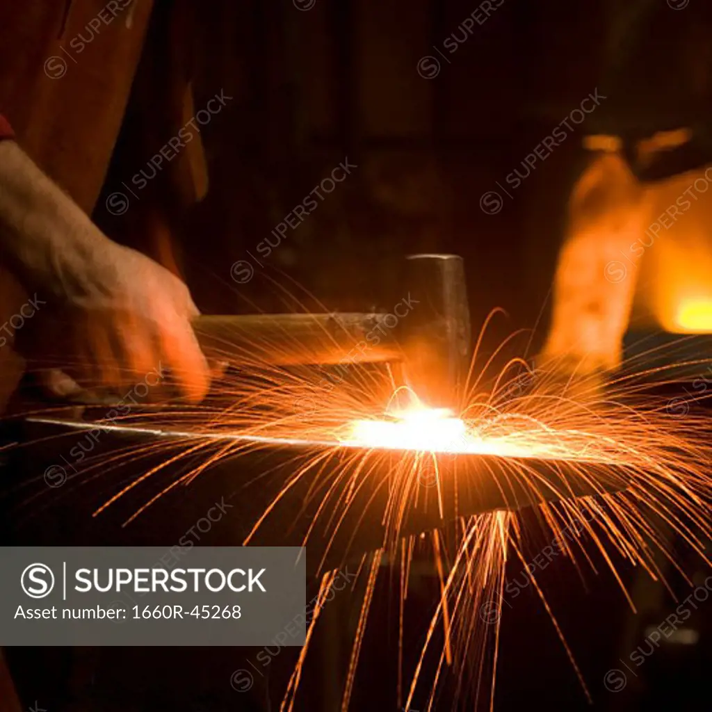 hammer striking a piece of hot metal on an anvil