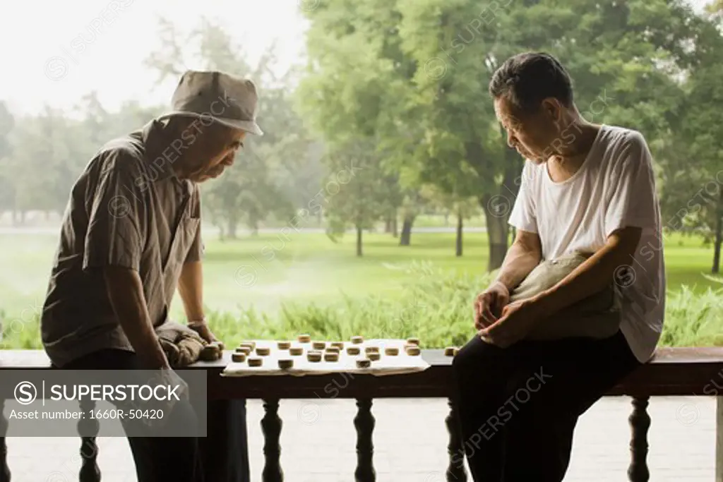 Two men sitting outdoors playing board game