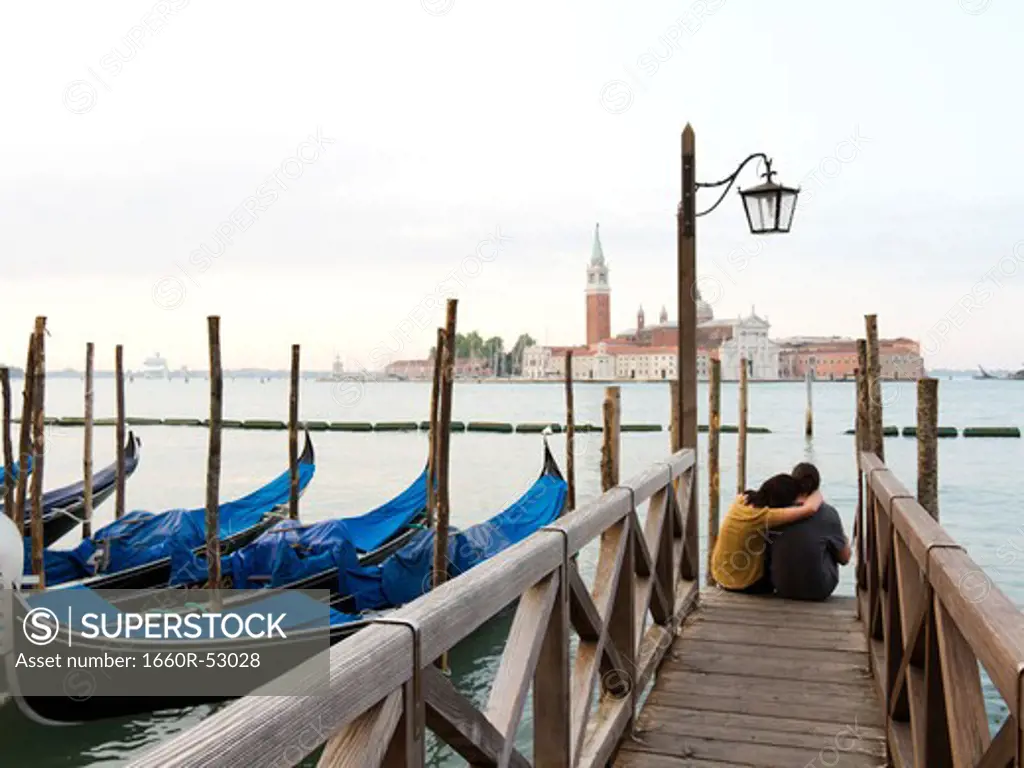 Italy, Venice, Young couple embracing by canal