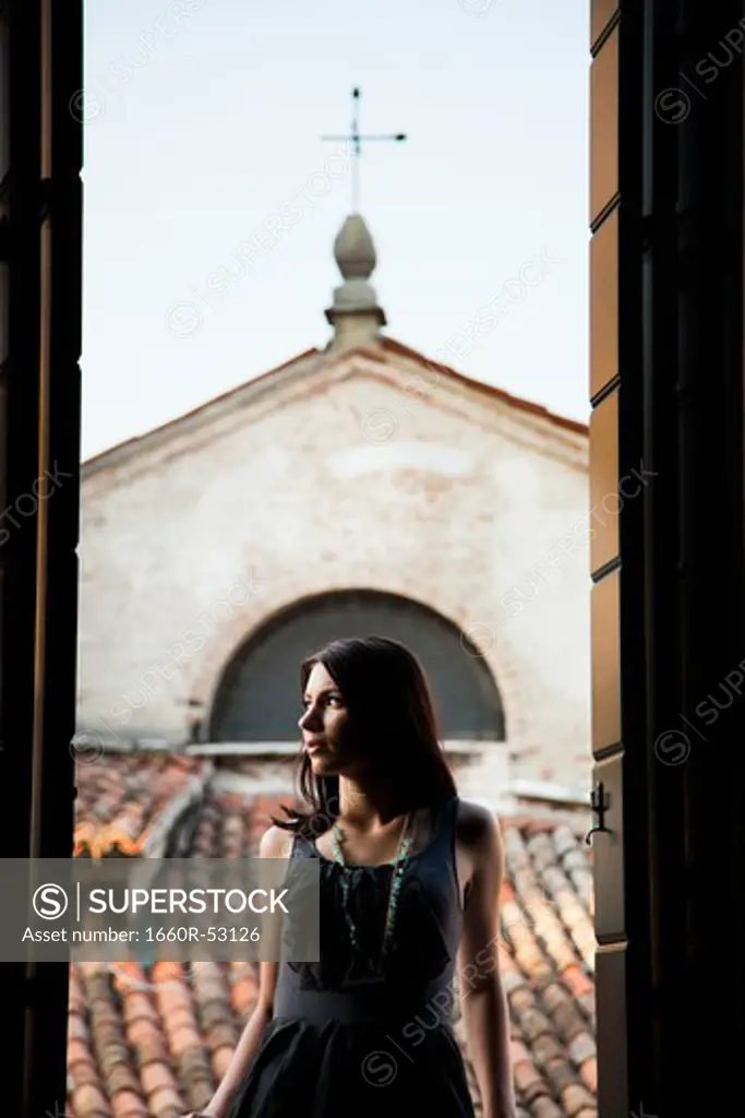 Italy, Venice, Young woman standing in balcony door, contemplating view