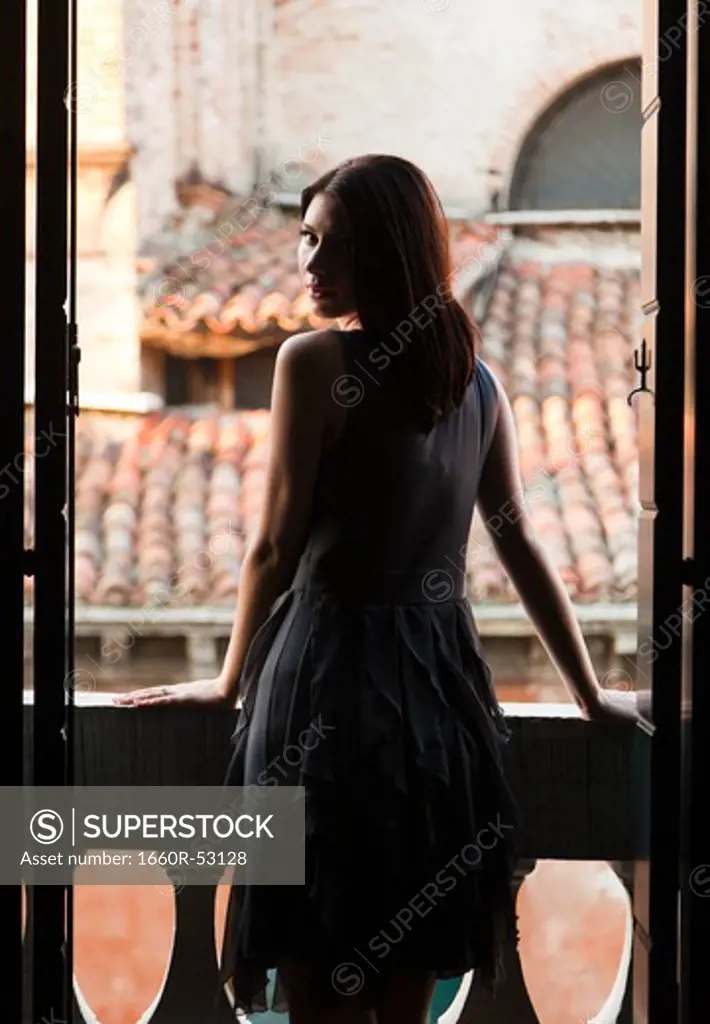 Italy, Venice, Young woman standing in balcony door