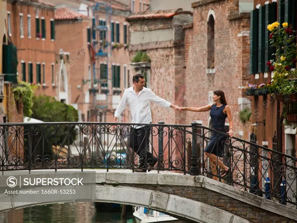 Italy, Venice, Romantic couple walking on footbridge over canal