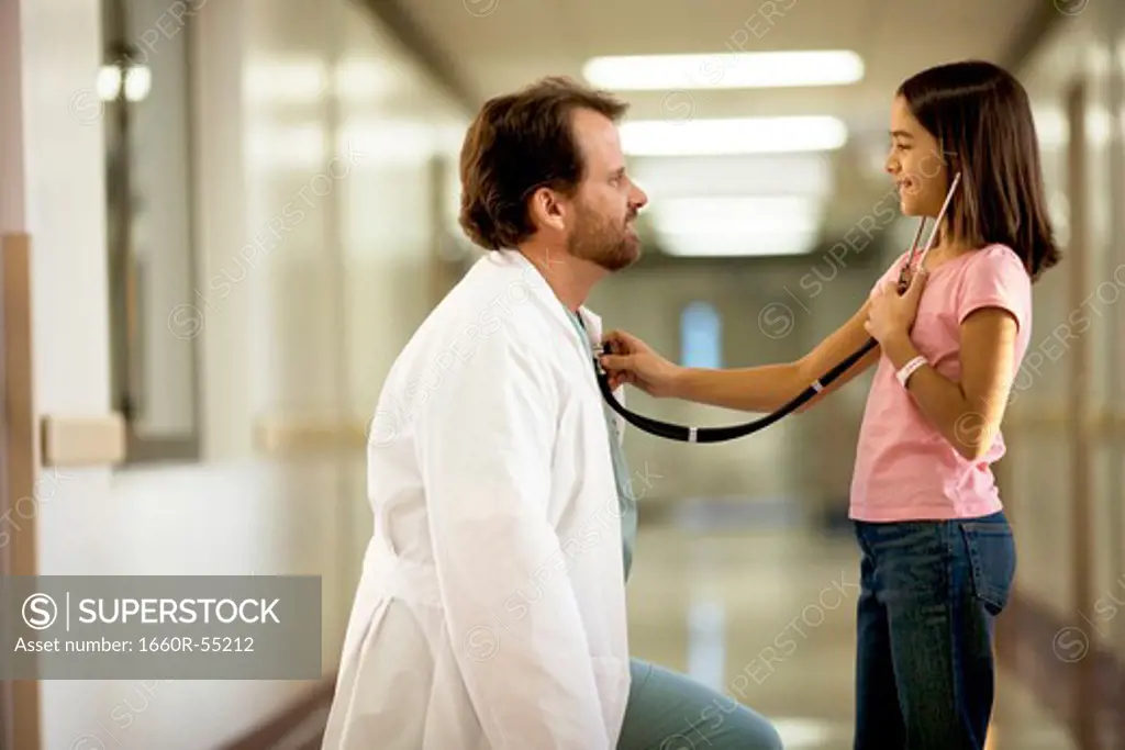 Young girl playing with female doctor's stethoscope