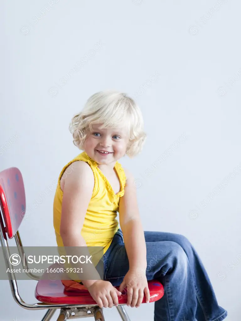 Girl (2-3) sitting on whoopie cushion, smiling, studio shot