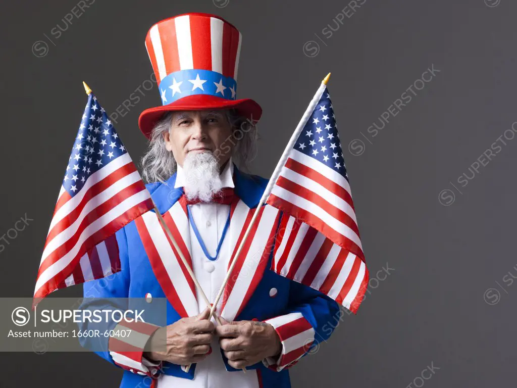 Man in Uncle Sam's costume holding american flags, studio shot