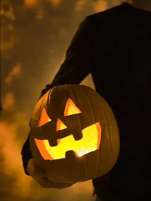 Mid section view of a person holding a Halloween lantern