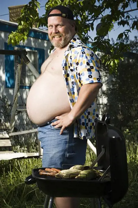 Overweight man by barbecue grill