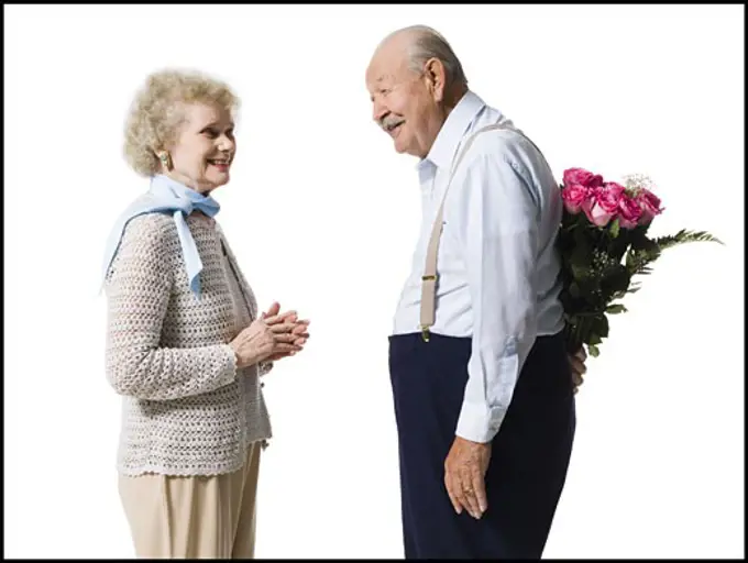 Older man with bouquet of pink roses behind back