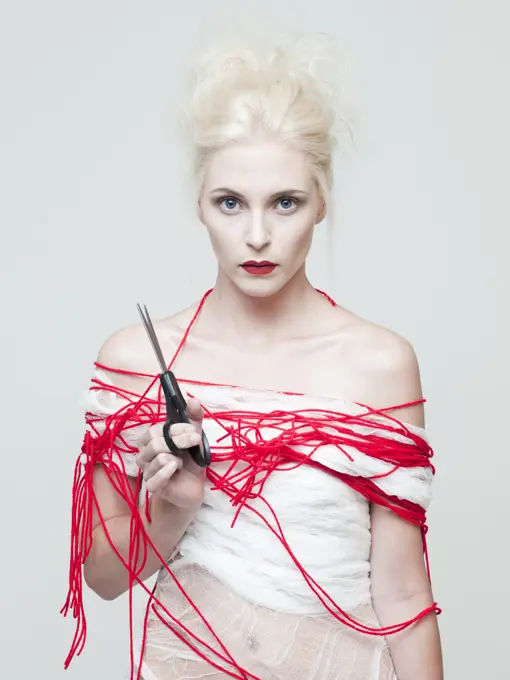 Studio portrait of young woman wrapped in red thread