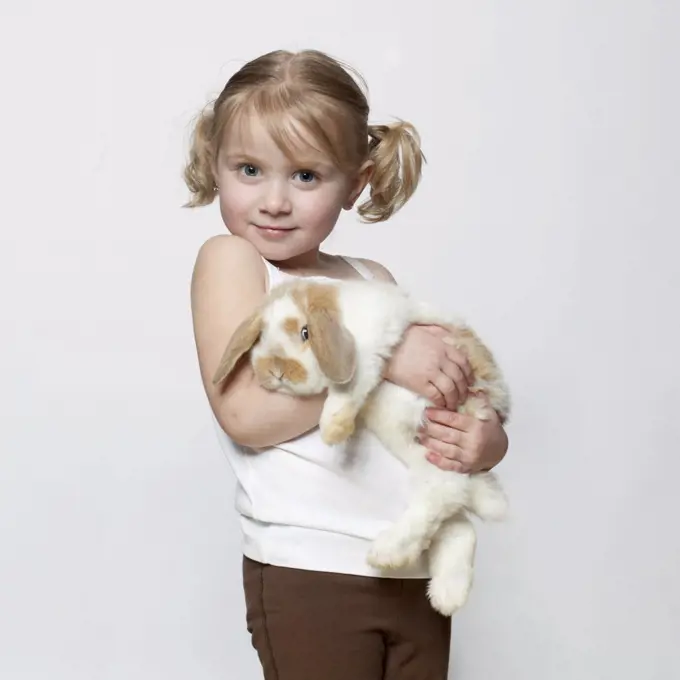 Studio shot of girl (2-3) holding rabbit