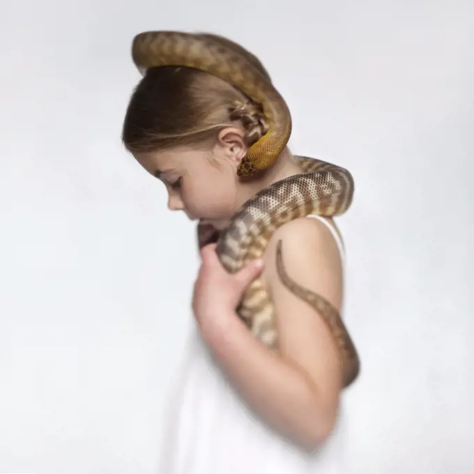 Studio portrait of girl (6-7) with snake