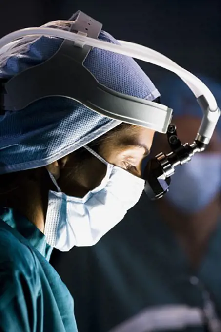 Female doctor in scrubs with head light in surgery