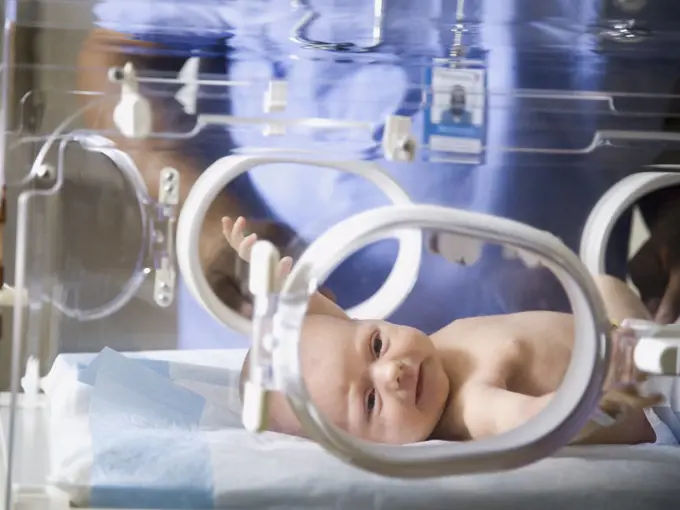 Baby in incubator with man in uniform