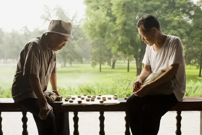 Two men sitting outdoors playing board game