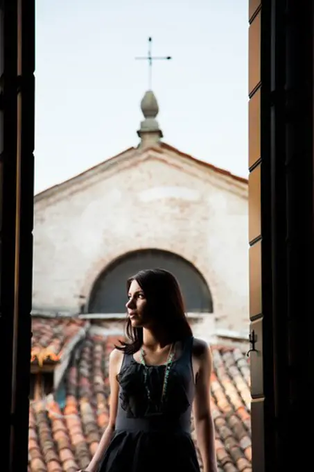 Italy, Venice, Young woman standing in balcony door, contemplating view