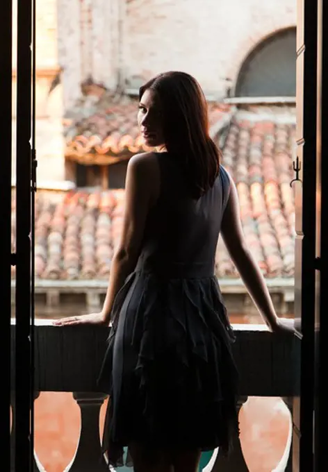 Italy, Venice, Young woman standing in balcony door