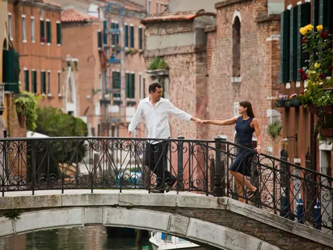 Italy, Venice, Romantic couple walking on footbridge over canal