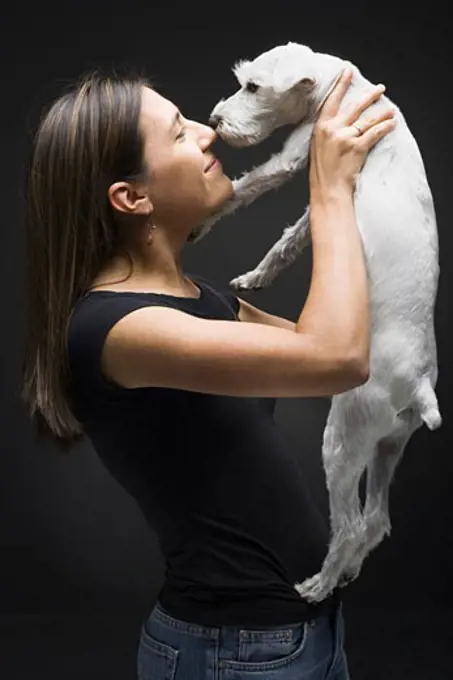 Profile of a young woman playing with her dog