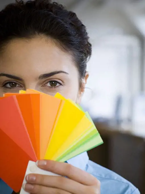 Portrait of a young woman holding color swatches in front of her face