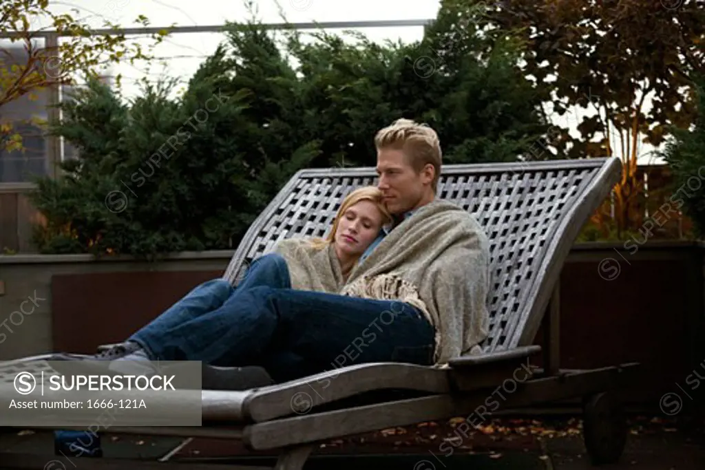 Young couple sitting in a lounge chair and cuddling