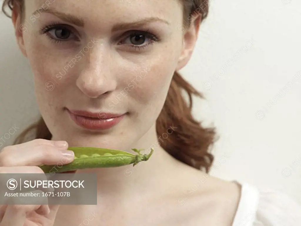 Young woman holding a pea pod