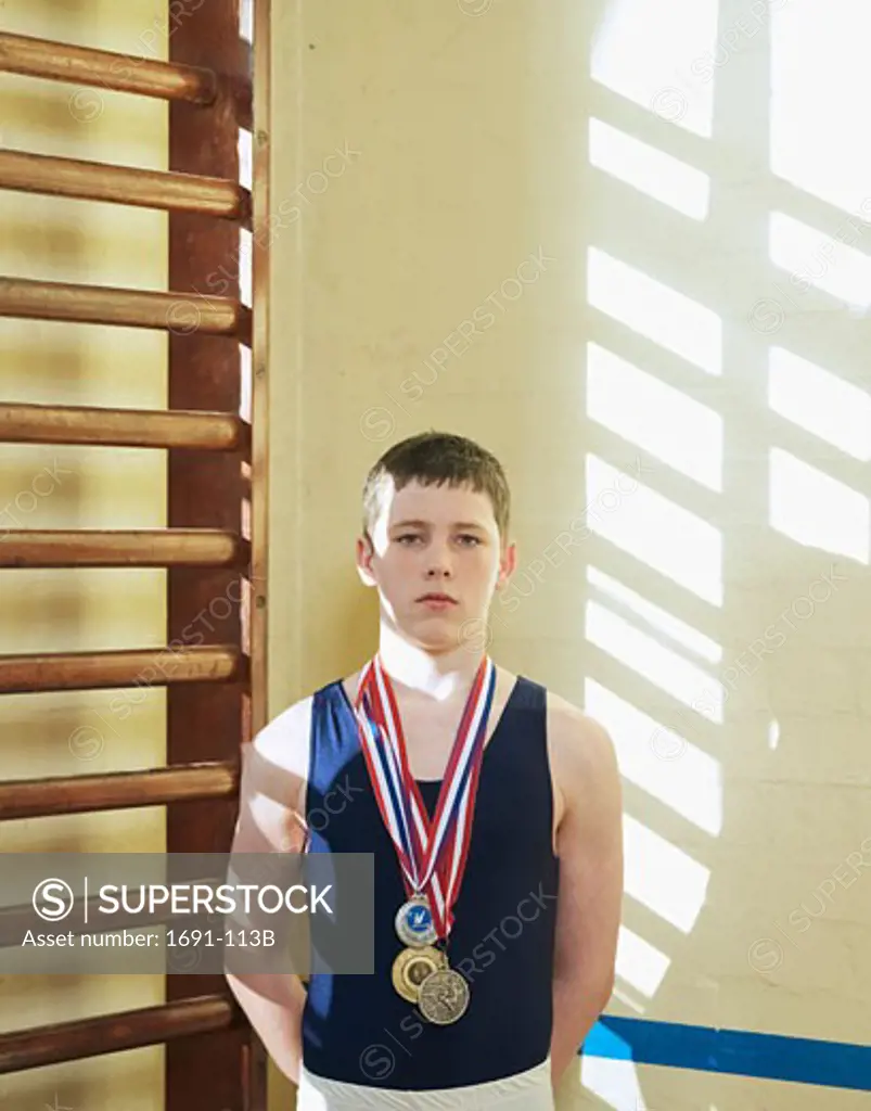 Male gymnast standing and wearing medals