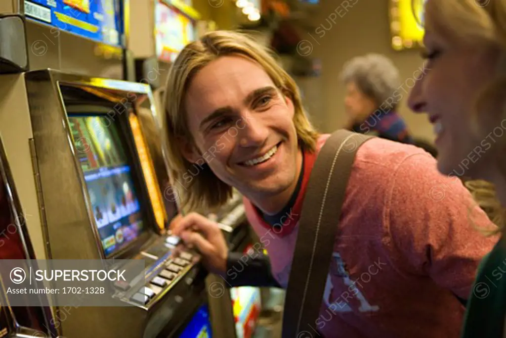 Young couple playing on a slot machine in a casino