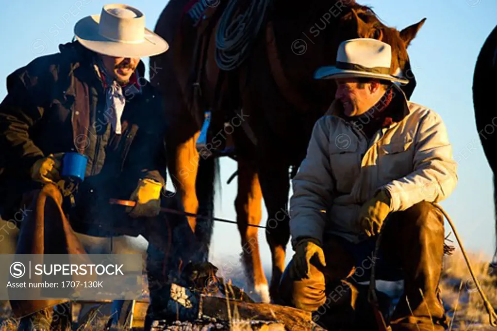 Two men sitting in front of a campfire