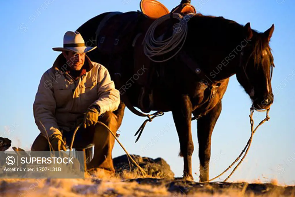 Mature man kneeling with a horse beside him