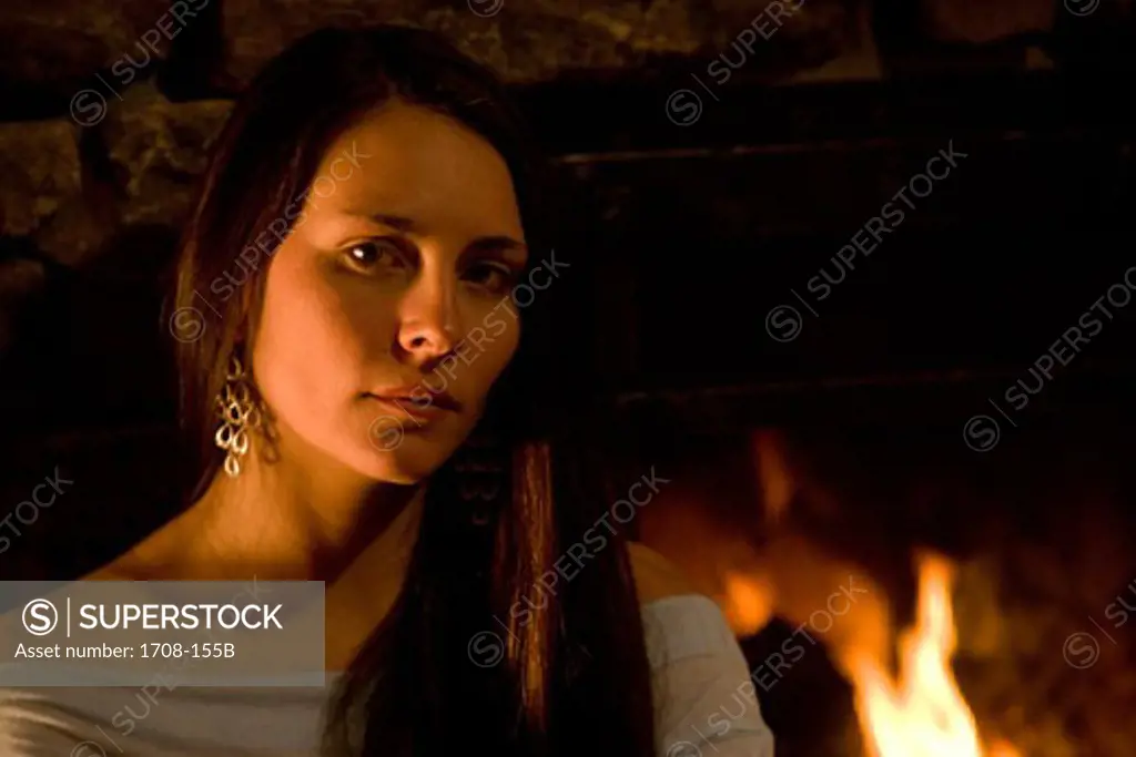 Portrait of a young woman in front of a fireplace