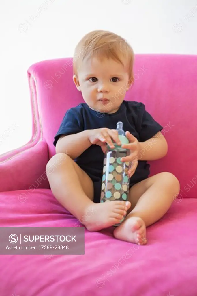 Portrait of a baby boy sitting with a baby bottle