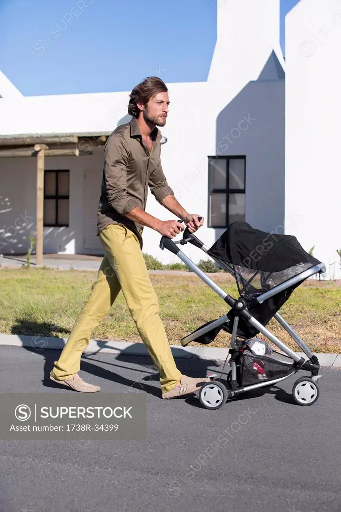 Man pushing a baby stroller on a road