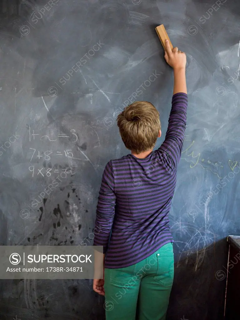 Boy cleaning blackboard with a duster in a classroom