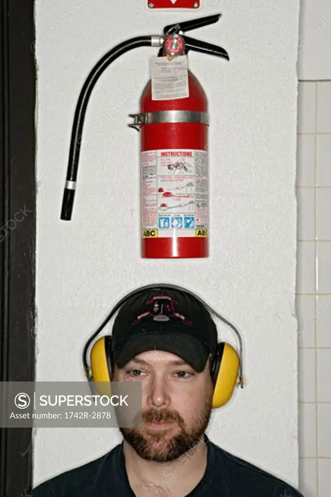 View of a man standing in front of a fire extinguisher.