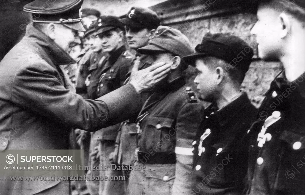 Adolf Hitler touches the face of Wilhelm Willi Hubner (1929-April 12, 2010) the youngest recipient of the Iron Cross. Dated 1945